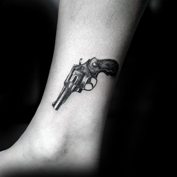 Tatuaje de pistola en el tobillo hombre