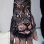 Tatuaje de león en la mano de ojos azules