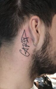 Tatuaje de grafiti detrás de la oreja hombre