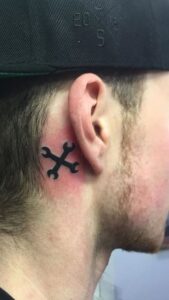 Tatuaje de herramienta detrás de la oreja hombre