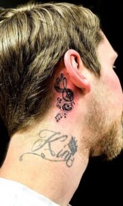 Tatuaje de nota musical detrás de la oreja hombre