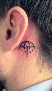 Tatuaje de paragua simple detrás de la oreja hombre
